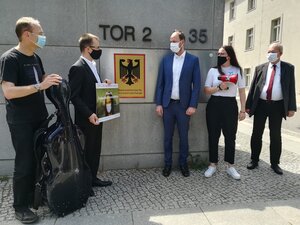 David Erler (mit Bildtafel) übergibt seine Petition symbolisch an Korbinian Wagner (blauer Anzug), rechts daneben mit Megaphon: Jessica Seip (OpenPetition)