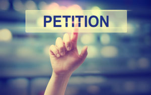 Ein Finger bedeutet auf ein Schild mit der Beschriftung "Petition"